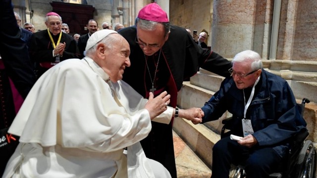 Francisco bendice a uno de los presentes desde una común postración física. Foto. Vatican Media.
