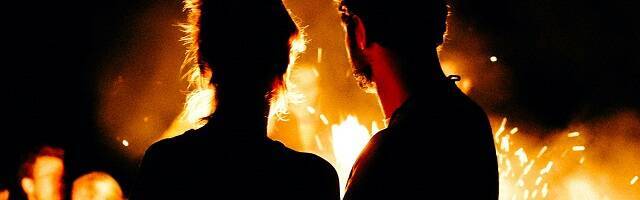 Dos personas silueteadas junto a una hoguera de noche, foto de Wesley Balten en Unsplash