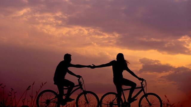 Dos jóvenes enamorados en bicicleta.