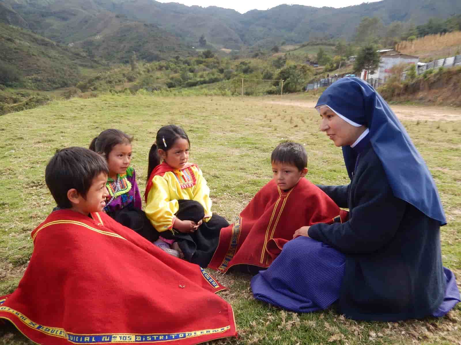 Una misionera de Jesús Verbo y Víctima con unos niños en una zona montañosa