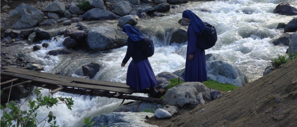 Religiosas Misioneras de Jesús Verbo y Víctima cruzando un río en un puente precario