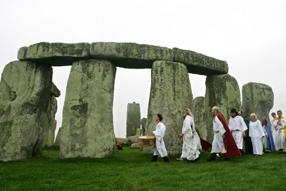 Ingleses modernos vestidos de druidas con tambor rodean Stonehenge
