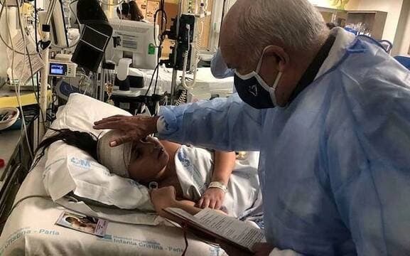 El padre Ángel Camino bendice a Teresita Castillo en el hospital