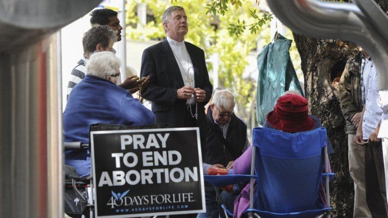 Obispo rezando frente a un abortorio