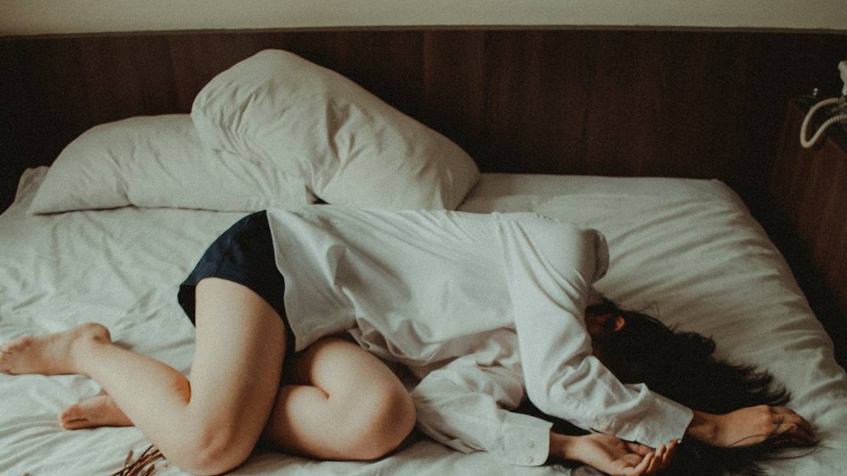 Mujer tendida en la cama con apariencia de estar deprimida.