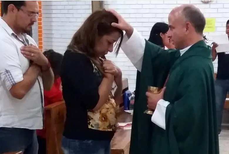 Un sacerdote bendice a una mujer que no puede comulgar en la fila de la comunión