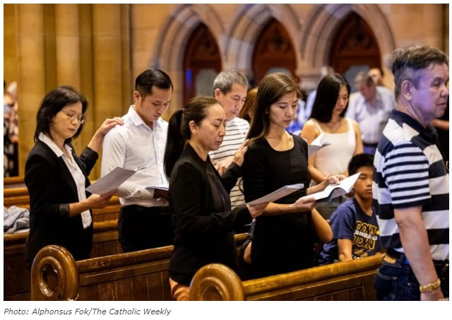 Padrinos ponen la mano sobre los candidatos a ser bautizados en 2024 en Sídney, muchos de origen chino o vietnamita