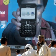 Pakistaníes frente a un anuncio de un teléfono móvil