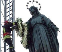 Un bombero de Roma deposita una corona de flores en lo alto del monumento a la Inmaculada