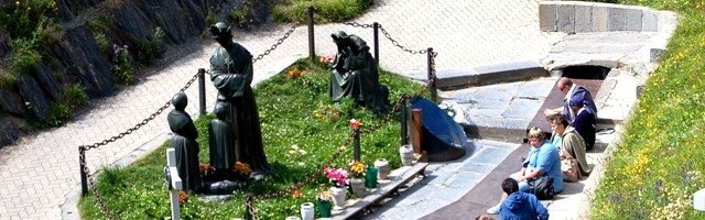 Peregrinos junto a las estatuas que representan a la Bella Señora -de pie y sentada llorando- y los dos pastorcitos videntes