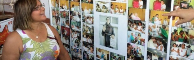 Doris Hipólito contempla el mural con fotos de niños salvados, con una imagen del popular San Frei Galvao en el centro