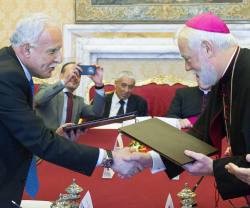 Monseñor Gallagher y el palestino Al-Malki intercambian las copias del acuerdo firmado