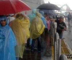 Los fieles esperan bajo el granizo y la lluvia para entrar en el espacio que acogerá la misa de Francisco en Quito