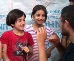 Unas niñas cristianas iraquíes desplazadas enseñan a contar hasta diez en árabe a un voluntario de CampamentoIrak