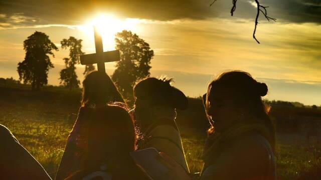Jóvenes peregrinos con una cruz, al atardecer.