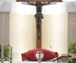 El Papa besa el altar de la capilla de Casa Santa Marta, detrás de la cruz