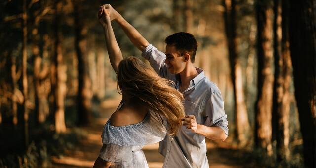 Una pareja danza en el bosque tomados de la mano en una foto de Scott Brume para Unsplash