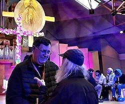 El sacerdote Álvaro Cárdenas conversa con un sin techo durante la reciente Jornada Mundial de los Pobres celebrada en Lourdes. Hogares Lázaro no solo ofrece ayuda material, sino que crea un hogar de convivencia con voluntarios en torno al Santísimo.