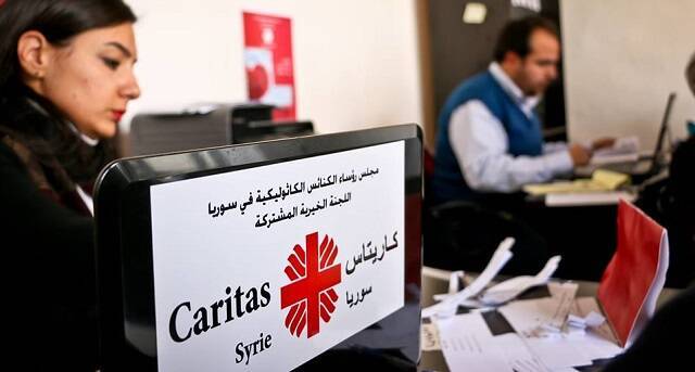 Una colaboradora junto a una caja de ayuda de Cáritas Siria