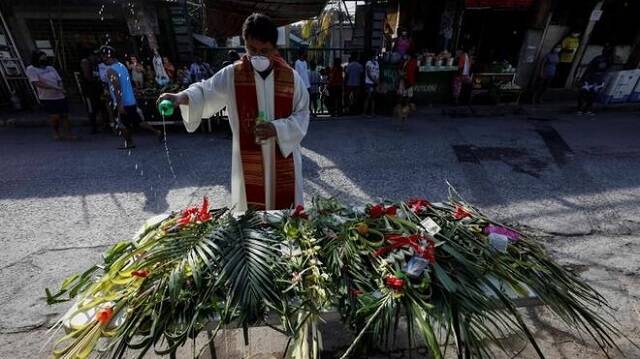 Sacerdote con mascarilla bendice palmas en el Domingo de Ramos de 2020, ya con mascarilla, en Filipinas