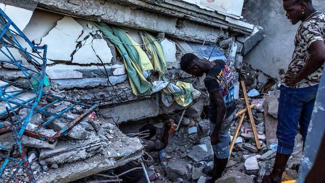 Tres hombres entre escombros del terremoto de Haiti.