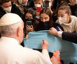Francisco firma una pancarta que traen peregrinos al Aula Pablo VI, donde impartió su catequesis de los miércoles
