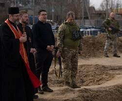 El arzobispo Shevchuk, con dos asistentes y militares ucranianos, ante la fosa común de Bucha el 7 de abril