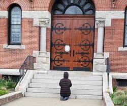 Una mujer reza ante la parroquia de Santa Teresa de Calcuta, en Dorchester, Boston, EEUU, cerrada por la pandemia, en 2020