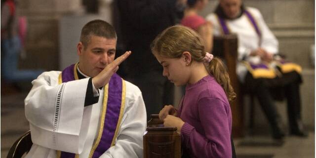 Un sacerdote imparte la absolución a una muchachita en confesión