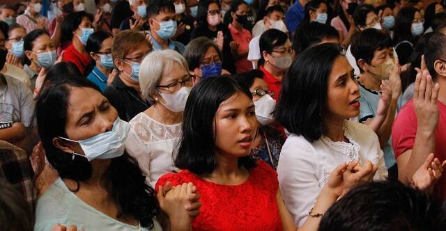 Filipinos en misa rezan con las manos levantadas el Padrenuestro