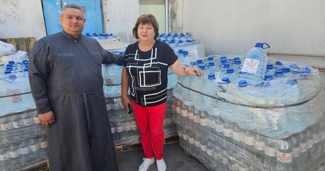 El padre Oleksander y una parroquiana de la parroquia de Berislav en Ucrania, en un reparto de agua
