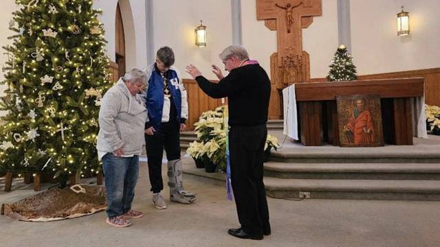 Un sacerdote bendice a una pareja lesbiana en el interior de una iglesia.