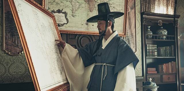 Un personaje coreano mira mapas en la película Nacimiento