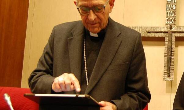 El cardenal Omella concentrado con una tablet en Conferencia Episcopal