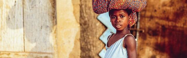 Una niña lleva cargas en la cabeza en Costa de Marfil... infancia y pobreza son temas de Dignitas Infinita... foto de Ben White en Unsplash