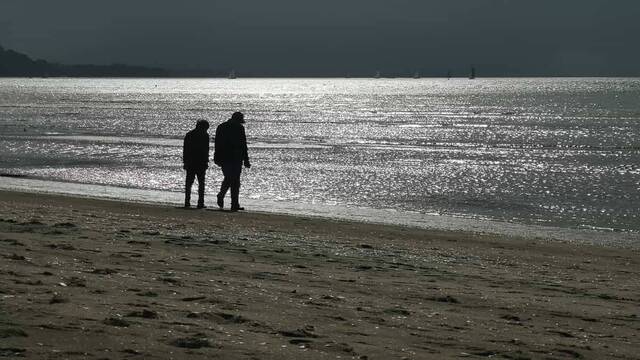 Dos ancianos caminando por la playa.