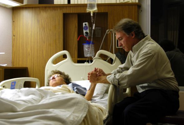 Un hombre acompaña a una enferma de edad avanzada en el hospital