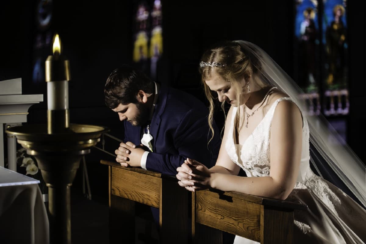 Un matrimonio recién casado reza, reclinados en la iglesia
