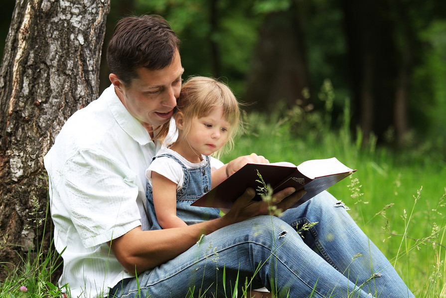Padre leyendo la Biblia con su hija. 