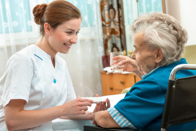 Una enfermera sonríe a una anciana en silla de ruedas