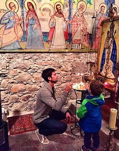 Djokovic enciende una vela a un icono junto con su hijo.