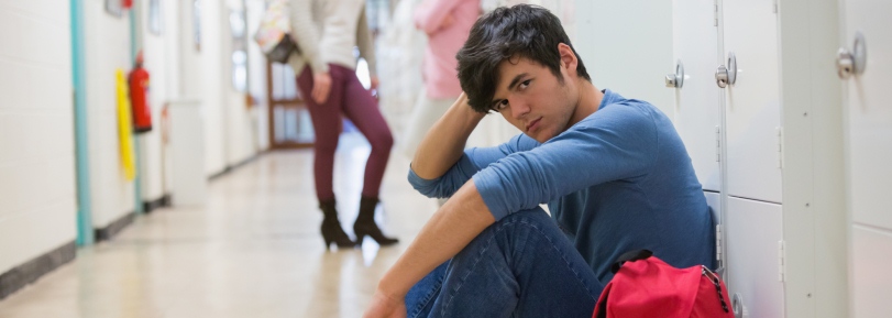 Un joven adolescente sentado en el pasillo del instituto