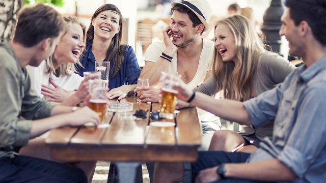 Grupo de amigos jóvenes toman cerveza y ríen