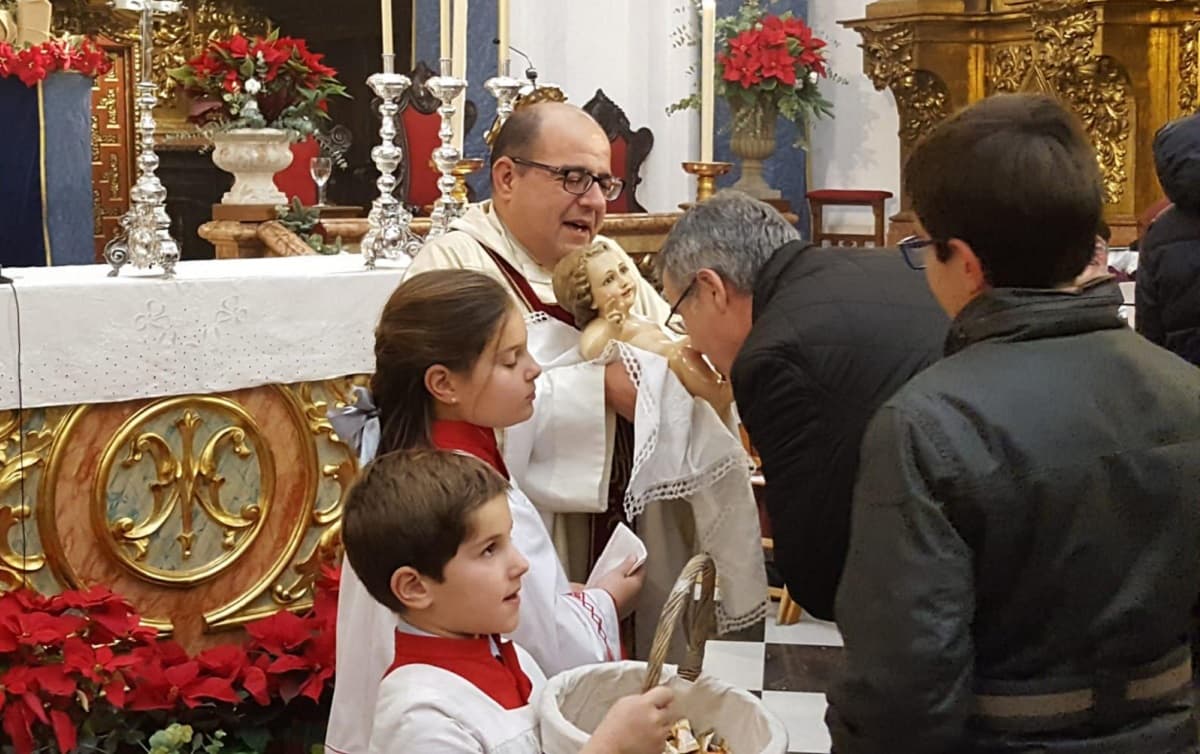 Una familia besa al Niño Jesús tras la misa