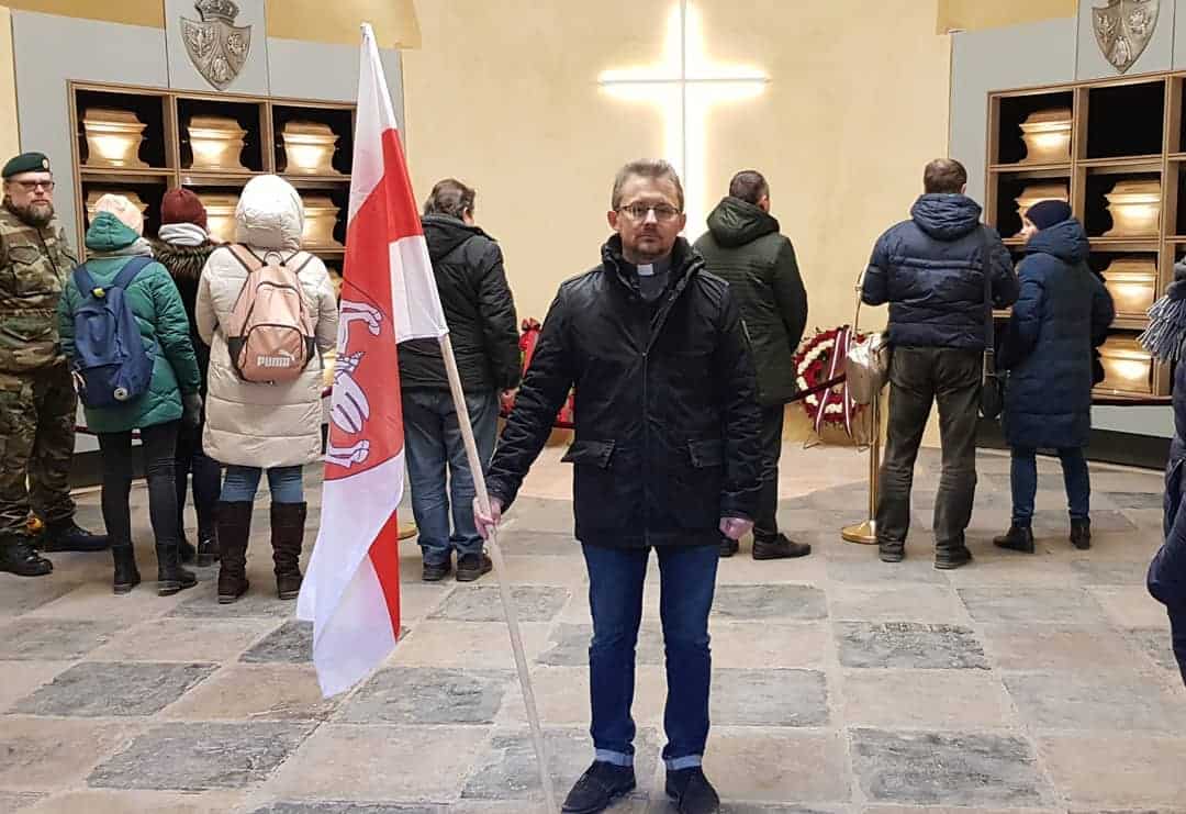 El padre Viacheslav Barok con la bandera blanca y roja en marzo 2020, antes de las elecciones y disturbios en Bielorrusia
