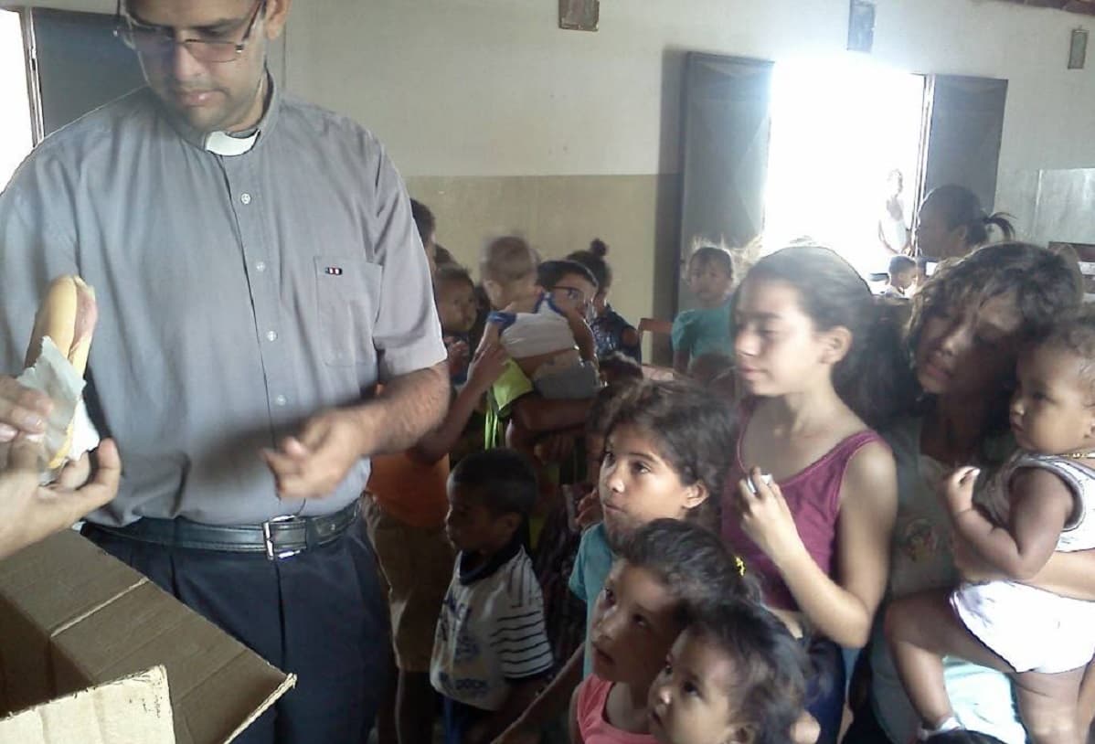 El padre Robinson dando bocadillos a niños venezolanos pobres.