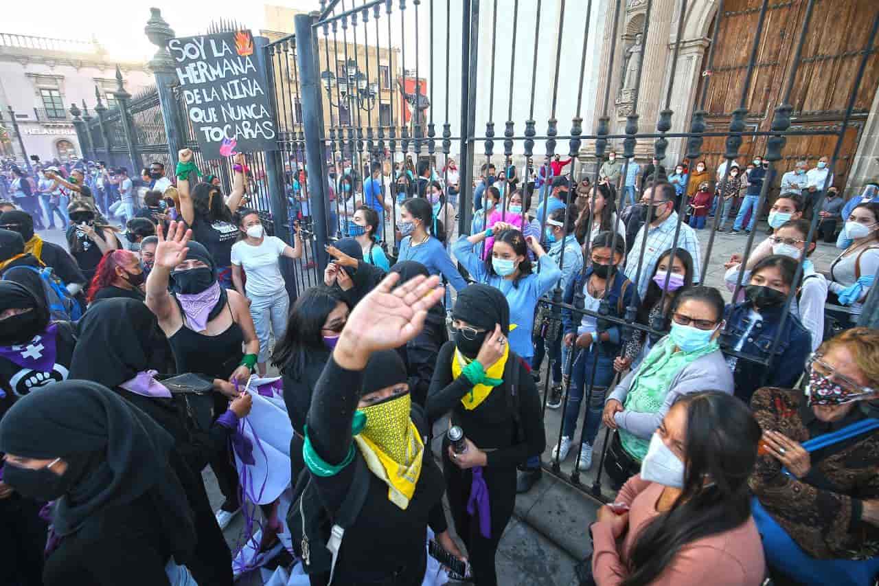 Católicos rezan protegidos de las feministas violentas por la verja de la catedral de Durango