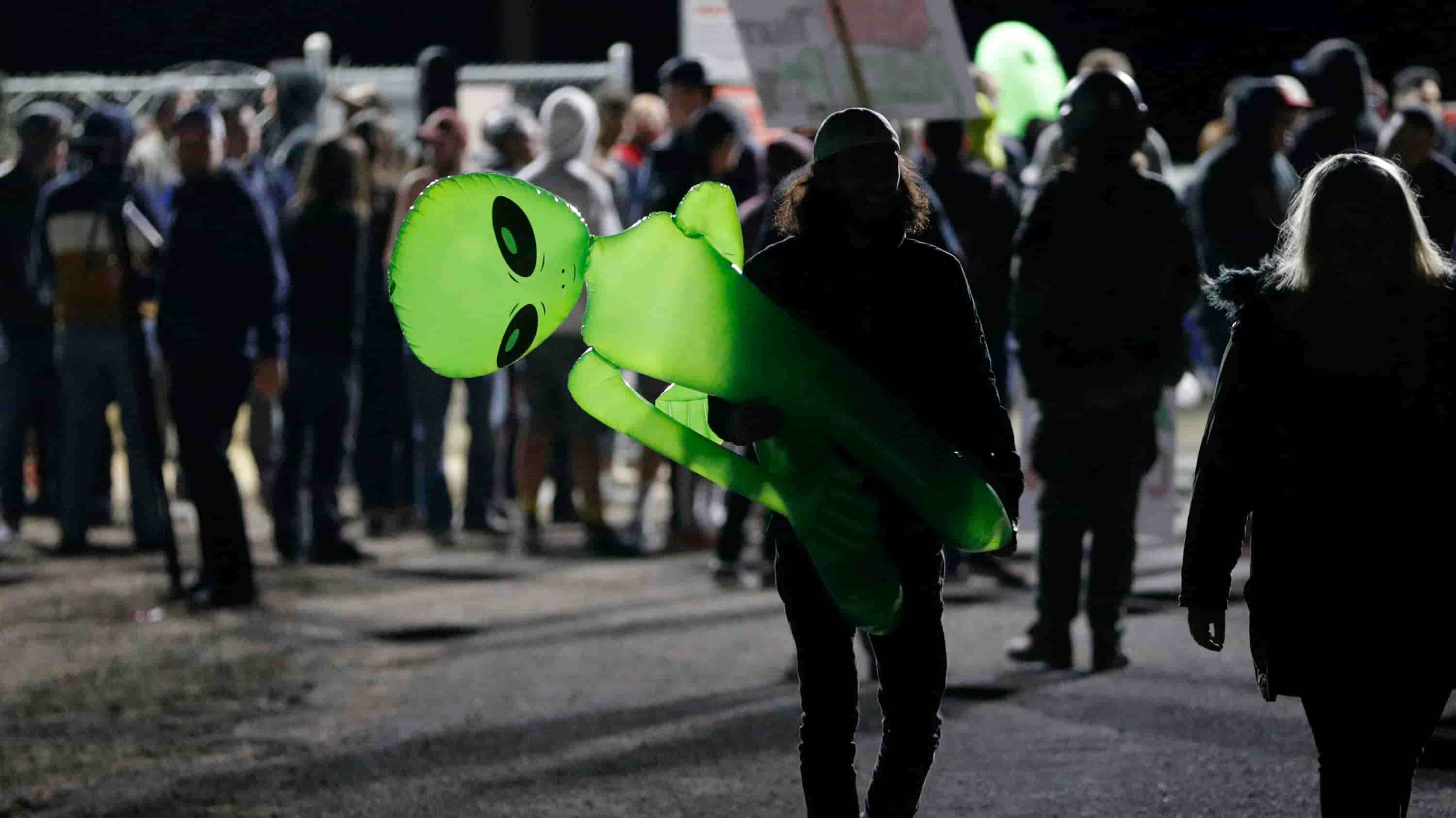 Un hombre de noche con un extraterrestre verde inflable