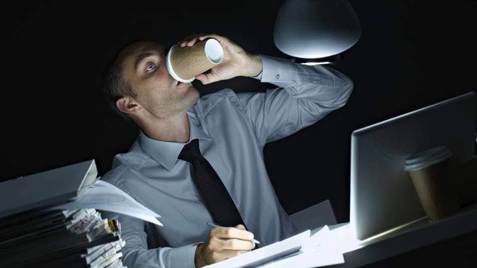 Un trabajoadicto de noche toma café en su escritorio