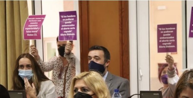 Activistas con carteles abortistas detrás de los concejales de Vox en el Ayuntamiento de Córdoba